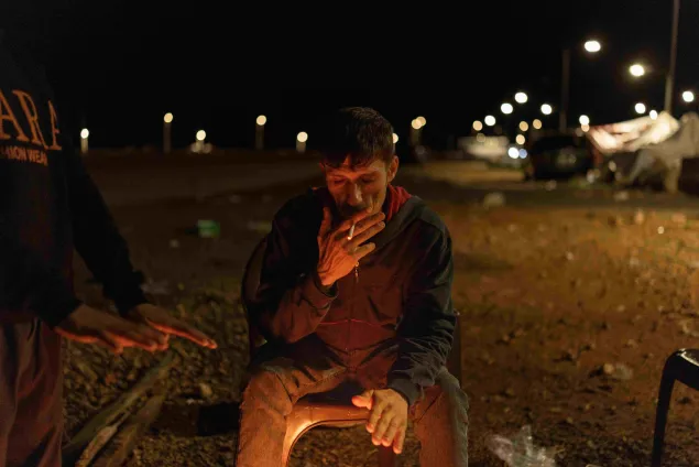 Haitham sits by a small open fire at night