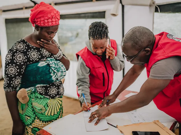 Noemie Niyongere, staff from the International Committee of the Red Cross (ICRC) assists Congolese refugee Annuarite Yamwaka 