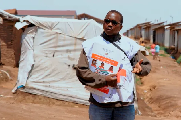 A Red Cross volunteer holds awareness-raising materials at a displacement site in the Democratic Republic of the Congo during Ebola community education activities.