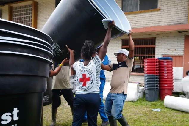 Trabajadores humanitarios del CICR sosteniendo un tanque para recolección de agua