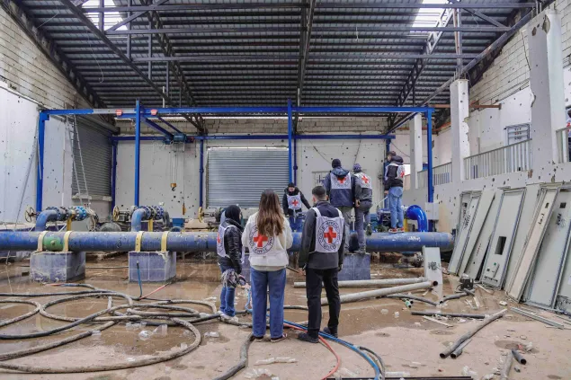ICRC staff inside a water treatment plant, surrounded by filtration equipment, pipes and industrial machinery.