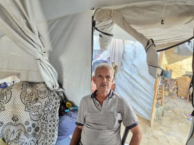 74-year-old Jihad Abu Awad rests on a chair in his tent in an IDP camp in Deir Al Balah.