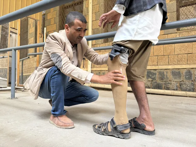 An ICRC Physical rehabilitation programmes specialist assisting a beneficiary with a prosthesis at Sana'a Physical Rehabilitation Center.