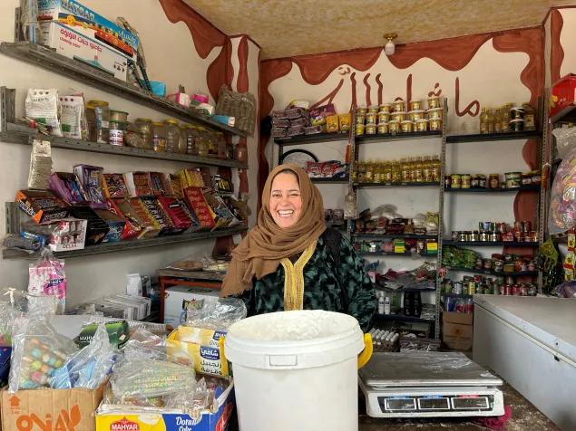 Nadwa sits in her shop, smiling at the camera