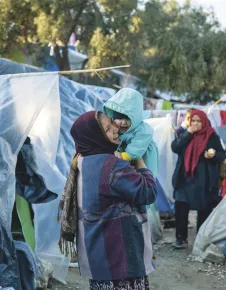 Lesbos, Moria, Olive Grove informal camp. A woman holds a baby in her arms.
