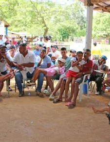 Una persona del CICR se dirige a una comunidad. De fondo se ven varias personas sentadas y prestando atención a la charla.