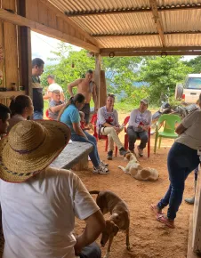 Personas de una comunidad rural en Colombia están sentadas en grupo mientras conversan con representantes del Comité Internacional de la Cruz Roja (CICR), en un entorno comunitario.