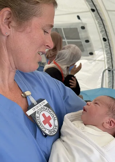 An ICRC nurse holding a newborn in her arms.