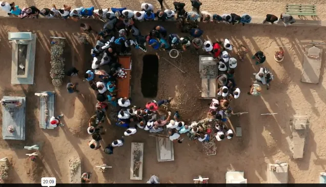 Group of people gathering around a coffin that will be buried 