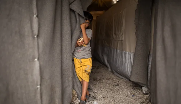 ICRC Greece Child next to a tent in ICRC camp in Greece