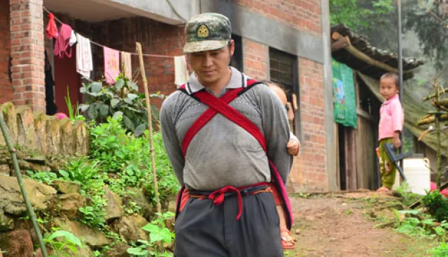 如果适应的好，患者在安装假肢后可以恢复大部分的日常生活。图为一名患者背着娃娃从坡上走下来。