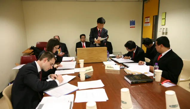 在香港进行的国际人道法模拟法庭比赛上,来自澳大利亚国立大学毕业班的学生肯德拉•富拉克和约瑟夫•克拉姆(左)作为控方选手与来自印度尼西亚加札马达大学代表队的学生展开辩论。