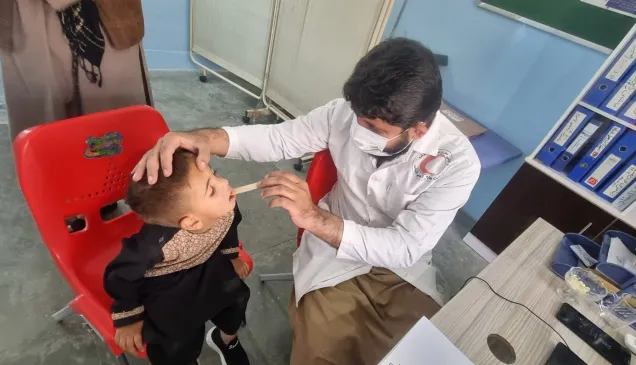 Little Khalid Ahmad is being medically examined by a health physician in an ARCS BHC in Kandahar