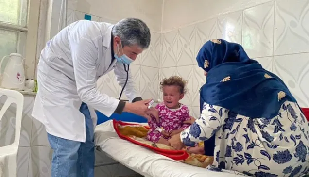 An Afghan Red Crescent Society (ARCS) doctor examines a patient at the Ghazi City Basic-Health-Care Centre