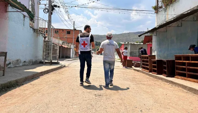 En Magdaleno, estado Aragua, uno de los participantes del proyecto de emprendimiento está caminando por la calle conversando con un trabajador del CICR.