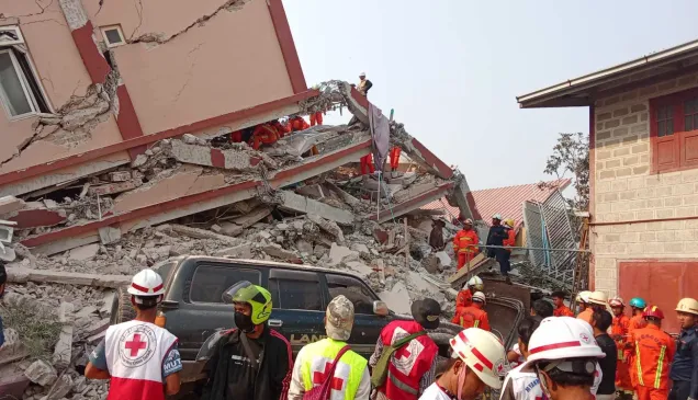 Colegas da Cruz Vermelha de Myanmar percorrem edifícios destruídos por terremoto.