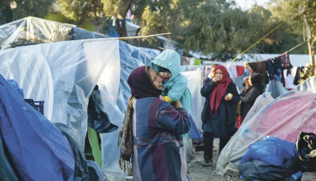 Lesbos, Moria, Olive Grove informal camp. A woman holds a baby in her arms.