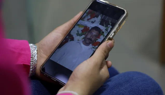 Lana Noamaan holding a smartphone showing a picture of her father