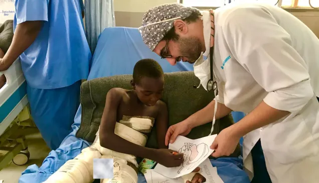 Egyptian anesthesiologist Dr. Aktham Al-Farnawani encourages a child to color after he was injured in an explosion in Maiduguri, Nigeria.