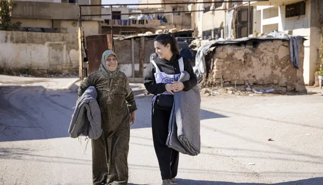 A staff member talks to a beneficiary during a distribution of aid items