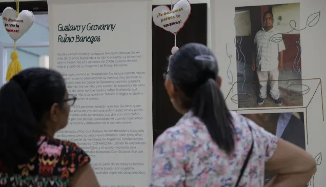 Dos personas son fotografiadas de espaldas mientras observan la exposición Tejer Memoria