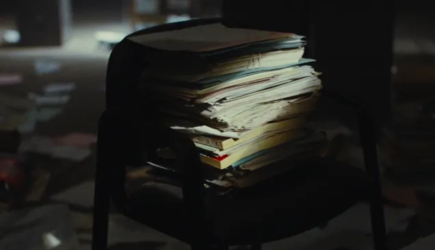 Imágen de carpetas y papeles sobre una silla. Las ilumina una luz tenue.