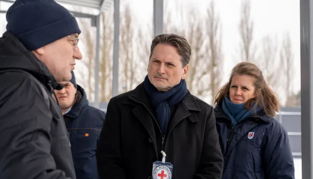 ICRC Director-General Pierre Krähenbühl speaks with a local resident outdoors in a winter setting, accompanied by a colleague.