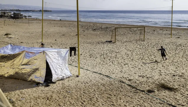 A boy plays football on the beach along the Corniche in Beirut, Lebanon, on March 7, 2026, next to a tent set up by a displaced family who had to move from Beirut’s southern suburbs following an evacuation order issued by Israel.