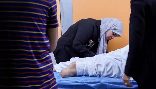 A physiotherapist wearing a headscarf supports a patient’s leg during a rehabilitation session at an ICRC-supported physical rehabilitation centre in Libya, with others observing nearby.