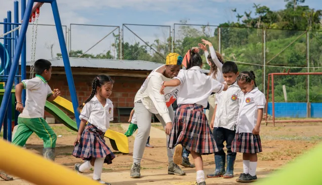 Niñas y niños juegan y comparten un momento junto a una persona del Comité Internacional de la Cruz