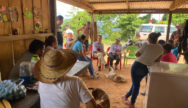 Personas de una comunidad rural en Colombia están sentadas en grupo mientras conversan con representantes del Comité Internacional de la Cruz Roja (CICR), en un entorno comunitario.