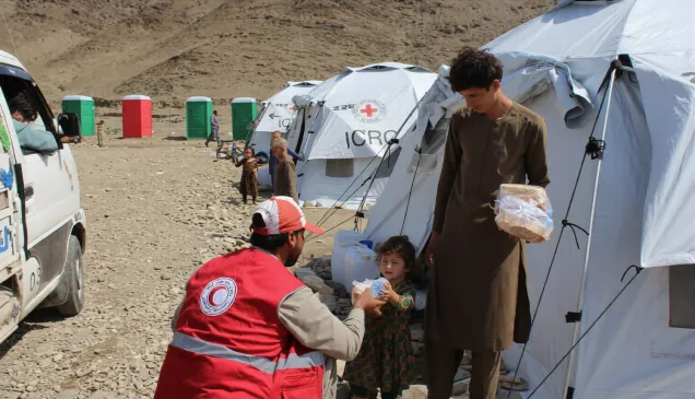 An Afghan Red Crescent Society volunteer provides food to a child at Chawkay camp in Kunar.