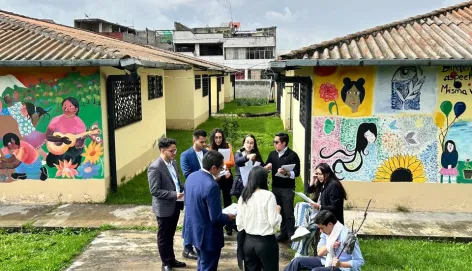 Jóvenes vestidos en un juego de roles interactúan en un jardín frente a unos murales.