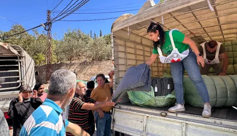 ICRC worker stands at the back of a lorry to unload blankets and essential items