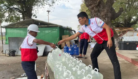 ICRC workers providing clean water containers in Myanmar