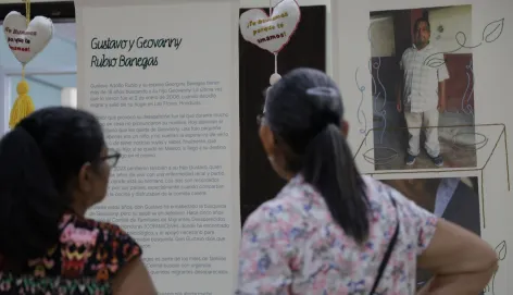 Dos personas son fotografiadas de espaldas mientras observan la exposición Tejer Memoria