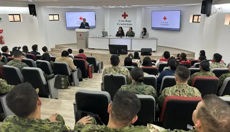 Un auditorio con miembros de las fuerzas armadas y un trabajador del CICR dando unas palabras.