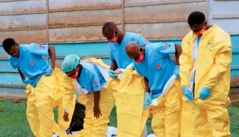 Red Cross volunteers in blue and yellow protective equipment prepare to carry out a safe and dignified burial during an Ebola outbreak in the Democratic Republic of the Congo