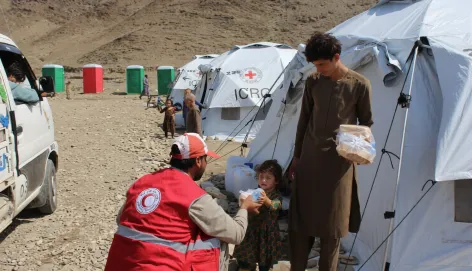 An Afghan Red Crescent Society volunteer provides food to a child at Chawkay camp in Kunar.