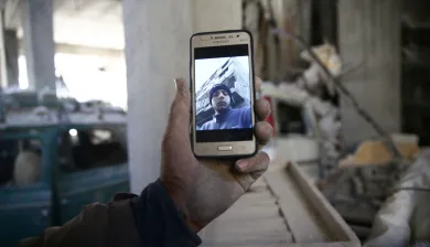 Abu Mohammad Alaya, 50, holds a mobile phone with a picture of his son Mohammad, who was killed in Douma on March 2, 2018.
