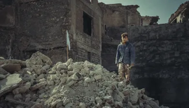 Garoto caminha sobre escombros.