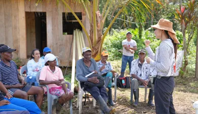 Una comuindad sentada que está escuchando a una persona del Comité Internacional de la Cruz Roja, que está frente a la comunidad dialogando con ellos.