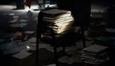 Folders on a chair, illuminated by a dim ray of light.