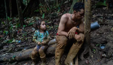 Photograph of child and man sitting on a fallen tree branch