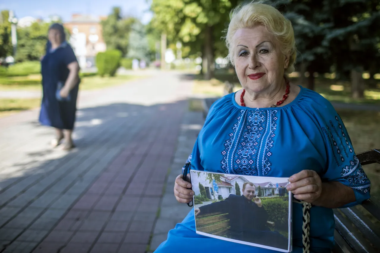 Lidiia Misiurenko stands in the Corpus Park in Poltava, holding a photo of her son, Borys