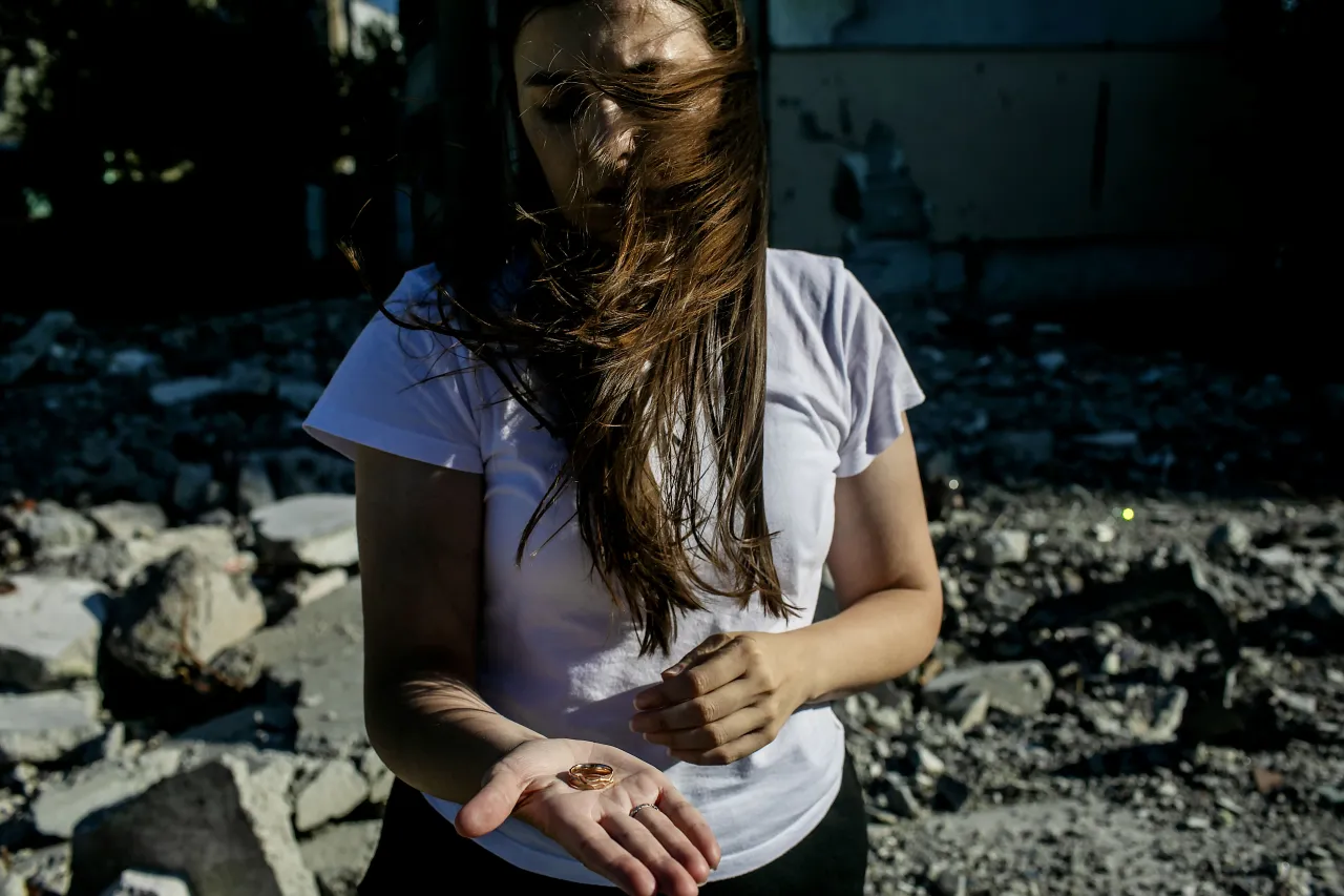 Svitlana is showing her husband's wedding ring at the location of a destroyed building in Saltivka, Kharkiv.