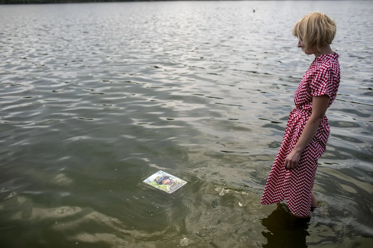 Nina stands in the middle of the Sviatoshynske Lake in Kyiv, holding a portrait of Vasil. The lake was one of their favourite spots, where she and Vasyl used to swim and spend time together.