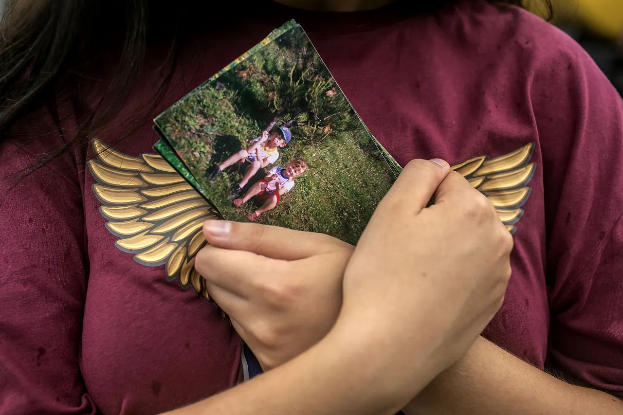 Olena holds a childhood photo of herself and her brother Andrii close to her chest at a train station in Kyiv. 