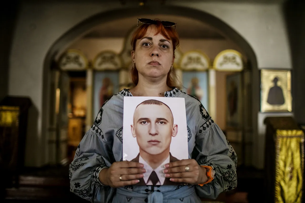 Antonina holds a portrait of her brother Mykola, in the Cathedral of Nativity in Korosten