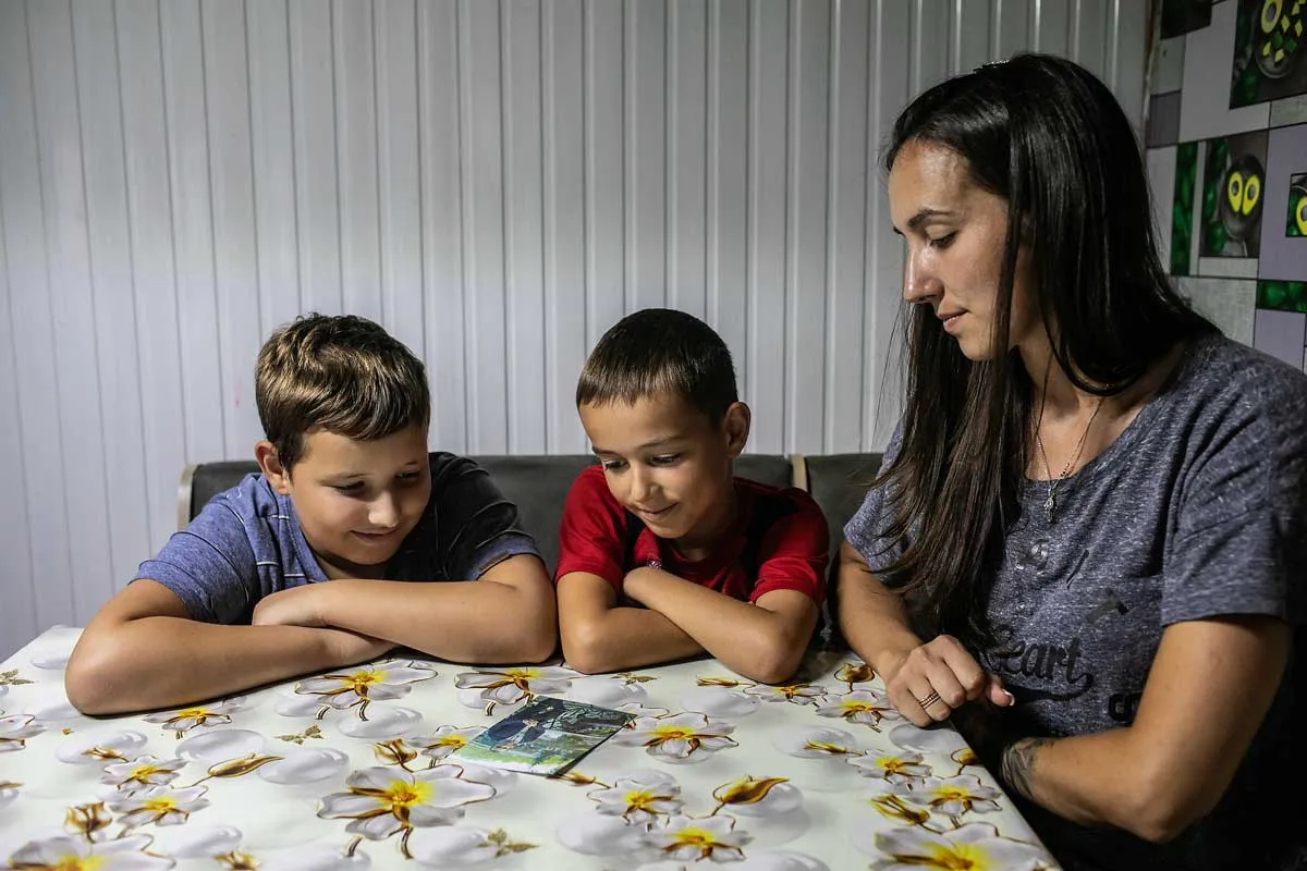 Viktoriia and her sons, Yaroslav and Denys, stand together, eyes fixed on a photo of their missing husband and father.
